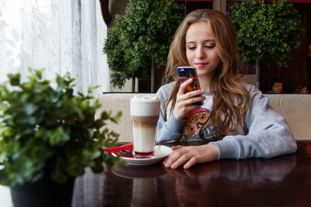 Young woman enjoying strong mobile connectivity while using her phone in a cafe